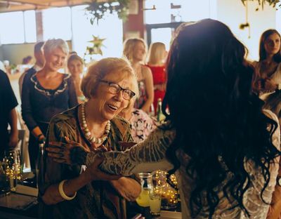 Elderly woman being congratulated for a milestone birthday by her young adult grand daughter