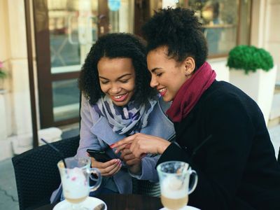 Two young ladies receiving a notification on their phone that SideQuest Events has created a new event on social media