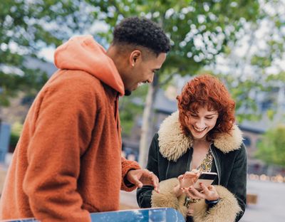 Man with skateboard and woman on phone smiling at receiving notifications from SideQuest Events social media about new private event packages