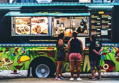 Three women placing orders in front of a food truck parked at a South Metro Denver event
