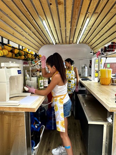 Two girls in a lemonade truck preparing beverages for their patrons